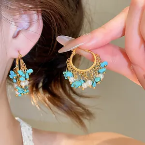 Gros plan de créoles plaquées or 18 carats avec glands en turquoise et perles
