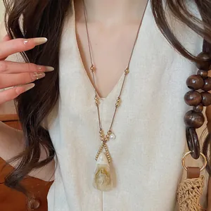 Vista detallada del collar con colgante de resina en forma de gota y cordón de cuero