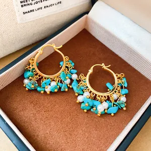 Gros plan de créoles plaquées or 18 carats avec glands en turquoise et perles fines