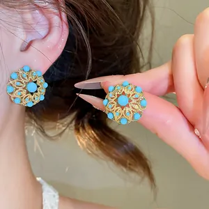 Détail de boucles d'oreilles vintage avec turquoise et filigrane doré sur l'oreille