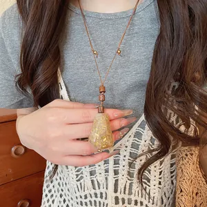Detalle del collar colgante de resina con copos de pan de oro y cuentas de madera