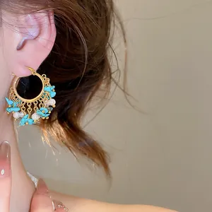 Détail de boucles d'oreilles créoles dorées vintage avec perles et pompons turquoise