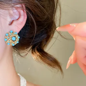 Détail de boucles d'oreilles vintage rondes en turquoise plaqué or 18k sur l'oreille du modèle