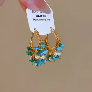Gros plan sur des créoles vintage dorées avec turquoises et détails de perles.