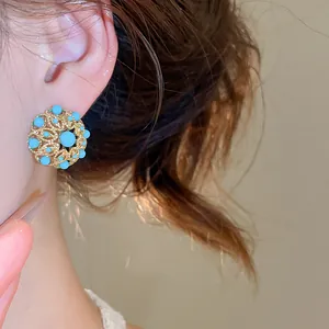 Vue macro de la texture d'une boucle d'oreille vintage dorée avec turquoise sur l'oreille