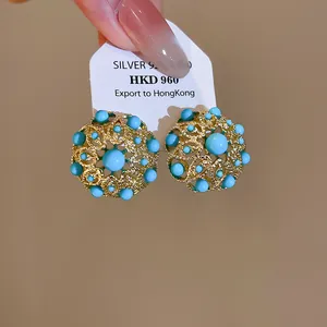 Gros plan de boucles d'oreilles rondes plaquées or 18 carats avec perles turquoise