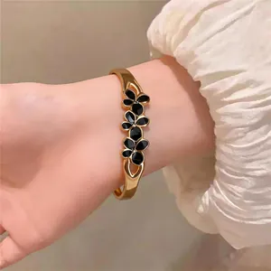 Bracelet élégant en acier inoxydable doré avec des fleurs en émail noir pour femmes