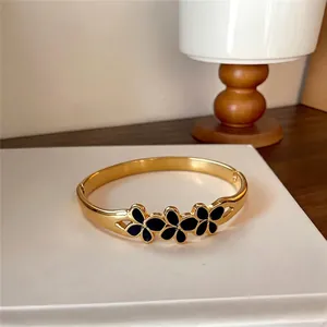Bracelet jonc élégant en acier doré avec motifs de fleurs en émail noir sur socle