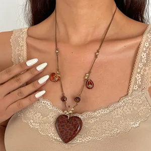 Close-up view of a vintage leopard print heart acrylic necklace worn by a model.