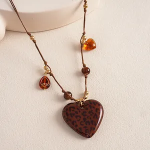 Close-up of a vintage leopard print heart pendant on a brown braided cord necklace.