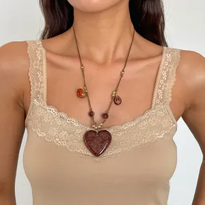 Macro detail showing a retro acrylic heart necklace with leopard print on a beige lace top