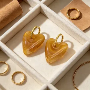 Nahaufnahme von marmorierten Bernsteinherz-Ohrringen mit goldenen Creolen in einer Schmuckdose