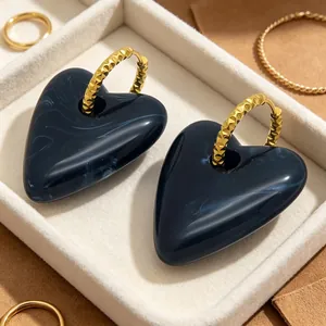 Nahaufnahme von marmorierten blauen Herzohrringen mit goldenen Creolen in einer Box