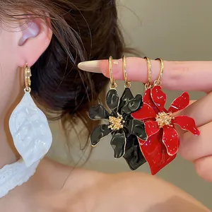Detalle de pendientes de aro asimétricos con diseño de flores y hojas de esmalte.