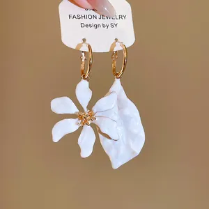 Primer plano de pendientes asimétricos de esmalte blanco con forma de flor y hoja