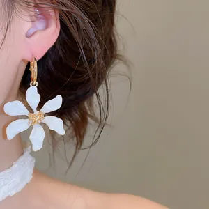 Primer plano de un elegante pendiente de flor de esmalte blanco con centro dorado