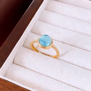 Primer plano de un elegante anillo abierto bañado en oro 18k con piedra celeste