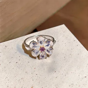 Detaillierte Nahaufnahme eines Blumenrings mit funkelnden Zirkonia und violettem Stein.