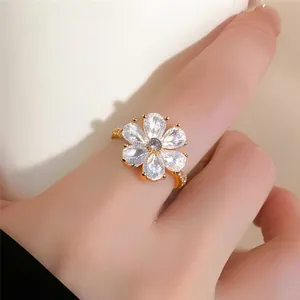 Nahaufnahme eines funkelnden, goldfarbenen Rings mit Zirkonia-Blume am Finger