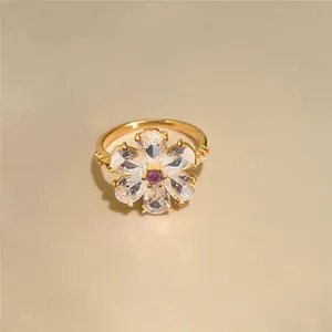 Makroansicht eines eleganten Blumenrings mit funkelnden klaren und lila Zirkoniasteinen