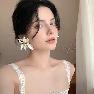 Primer plano de elegantes pendientes de flor de lirio blanco en una modelo asiática