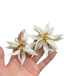 Elegantes pendientes de botón con flores de acrílico blanco y diseño de pétalos detallado.