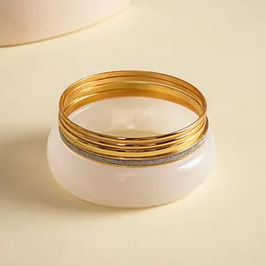 Detail van een 5-delige retro set met goudkleurige metalen en witte hars armbanden