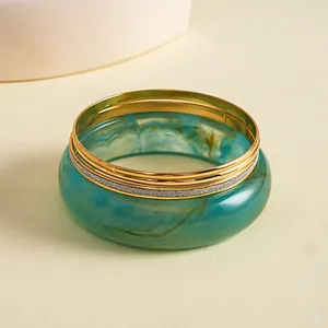 Macro-weergave van texturen van vintage hars gemarmerde armband en gouden metalen ringenset