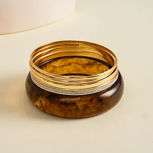 Detailweergave van een 5-delige retro set met bruine hars en goudkleurige armbanden