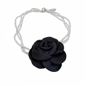 Collier de perles à plusieurs rangs avec un grand pendentif rose en tissu noir.