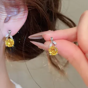 Nahaufnahme von eleganten Blumen-Ohrhängern mit gelbem Zirkon, am Ohr getragen und gehalten