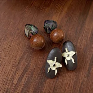 Vintage wooden orchid oval earrings and heart shell bead studs on a textured wood background