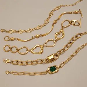 Detalle de varios brazaletes de acero inoxidable dorado con eslabones geométricos y piedra verde.