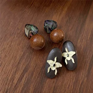 Macro detail of vintage wooden earrings featuring heart studs and orchid relief designs