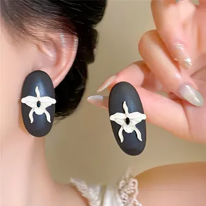 Close-up of vintage wooden stud earrings with silver needle and white orchid detail.