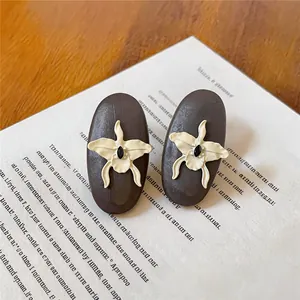Macro view of vintage style oval wooden stud earrings with creamy white orchid flowers