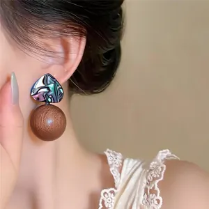 Close-up of retro wooden ball stud earring with iridescent heart accent on model.