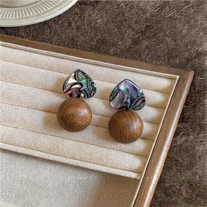 Detailed view of heart-shaped abalone shell earrings with round wooden beads