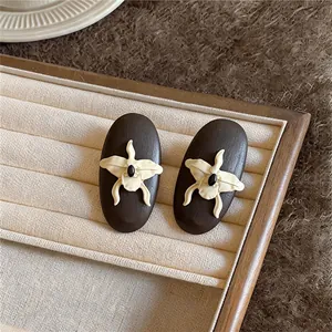 Close-up of retro oval wooden earrings with cream orchid flower relief details