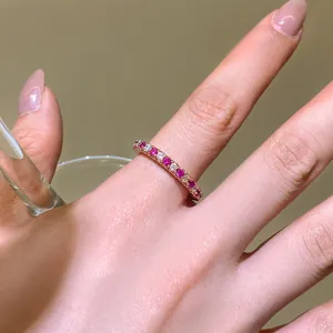 Vue détaillée d'une bague élégante en or rose avec zircons roses et blancs au doigt.