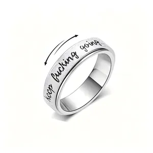 Close-up detail of silver stainless steel spinner ring with keep fucking going engraving