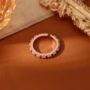 Détail d'une bague ouverte élégante en or rose avec des zircons rouges et blancs.