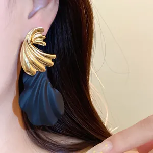 Detail von übertriebenen schwarzen Muschel-Resin-Ohrringen mit goldenem Metallic-Finish.