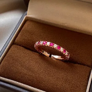 Gros plan d'une bague ajustable en or rose avec zircons roses dans son écrin de luxe brun.
