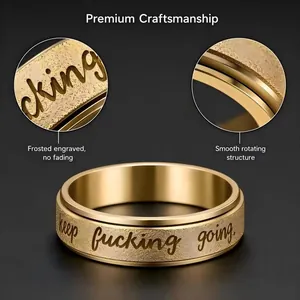 Close-up detail of 'keep fucking going' engraving on a gold stainless steel spinner ring