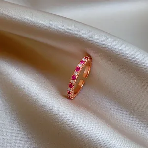 Gros plan d'une bague ouverte en or rose avec zircons roses et blancs sur de la soie.