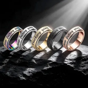 Close-up of stainless steel spinning rings with 'keep fucking going' engraving in 5 colors
