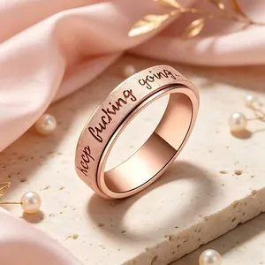 Close-up of rose gold spinner ring with 'keep fucking going' engraving and matte finish