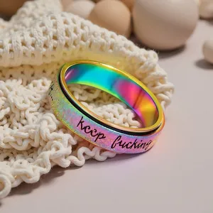 Close-up of iridescent rotatable stainless steel ring with Keep fucking engraving.