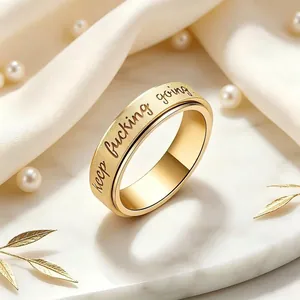 Close-up detail of a gold stainless steel rotatable ring with keep fucking going engraving